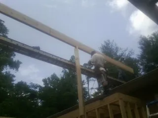 Carpenter setting a ridge beam over a new addition frame — Ice Dam Removal by Roofing Brothers in Miamiville
