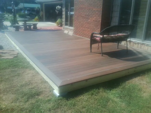 New wood deck and wicker chair beside a brick house in Miamiville