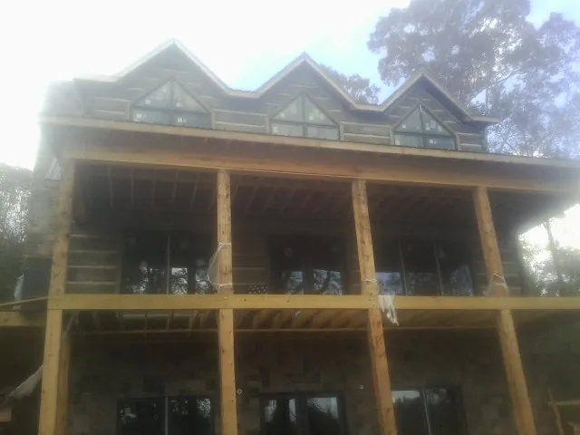 Dormers and porch framing on a large log home under construction — Roof Coating work by our crew in Miamiville