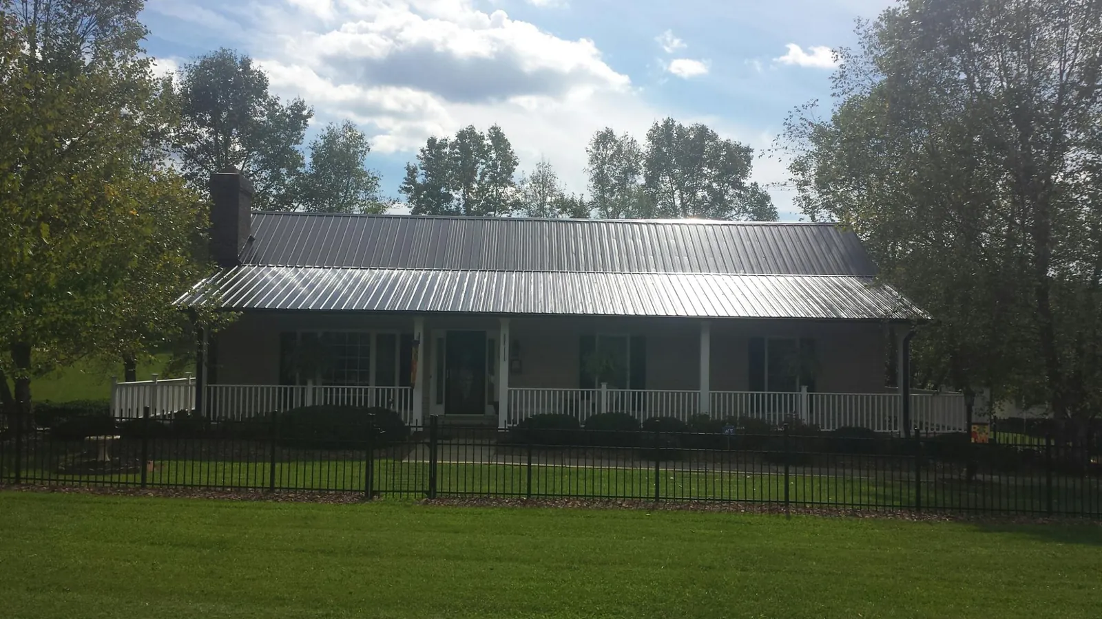 Gray metal roof on a brick ranch with a full width front porch — Gutter Guard Installation work by our crew in Miamiville