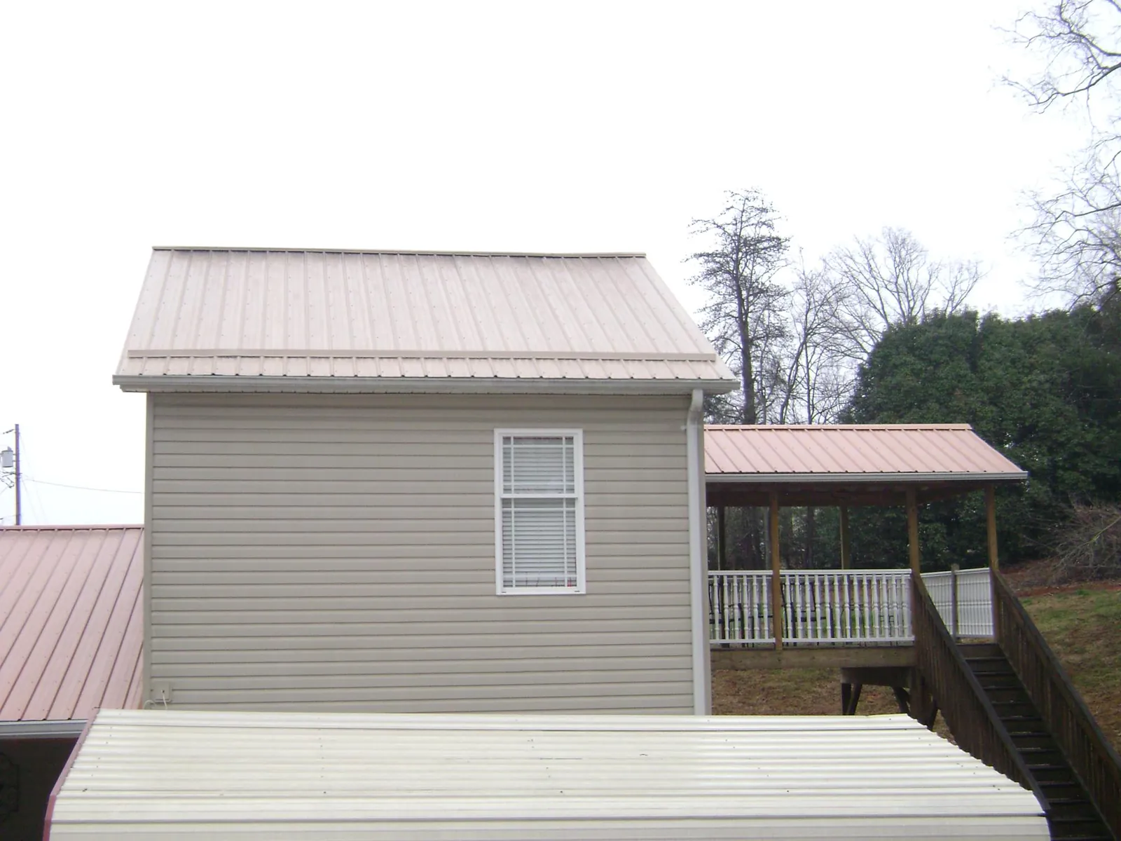 Tan metal roofs on a two story addition and attached porch, from a Roof Replacement job in Miamiville
