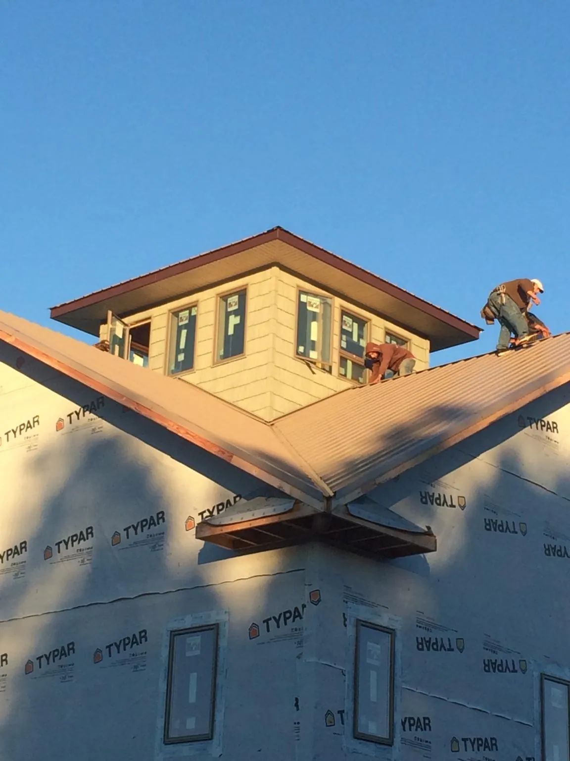 Roofers working around a rooftop cupola on a new metal roof at sunset — Roof Waterproofing in Miamiville by Roofing Brothers